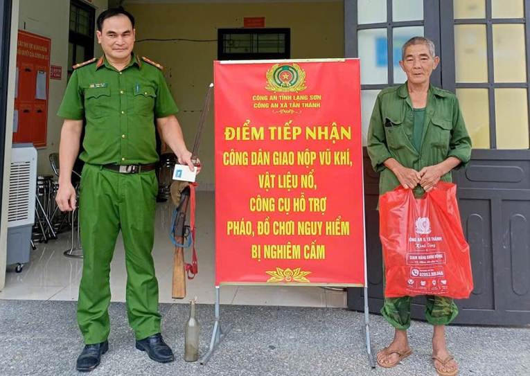 Người dân giao nộp vũ khí và nhận quà từ Công an xã.