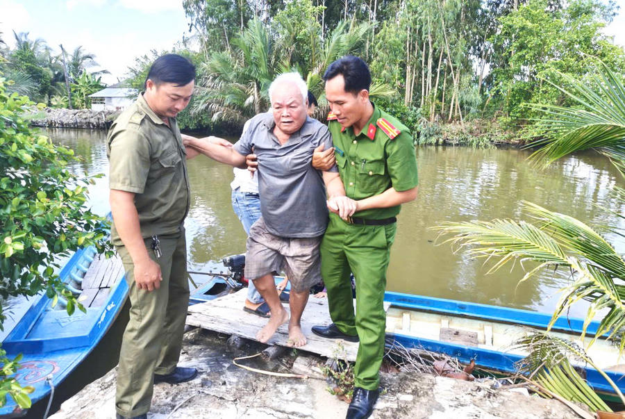Cán bộ Công an xã Vĩnh Lộc cùng lực lượng tham gia bảo vệ an ninh, trật tự ở cơ sở hỗ trợ ông Lê Quang Hung (ngụ ấp Vĩnh Thạnh, xã Vĩnh Lộc) thu nhận mẫu ADN (Ảnh: Hữu Đệ).