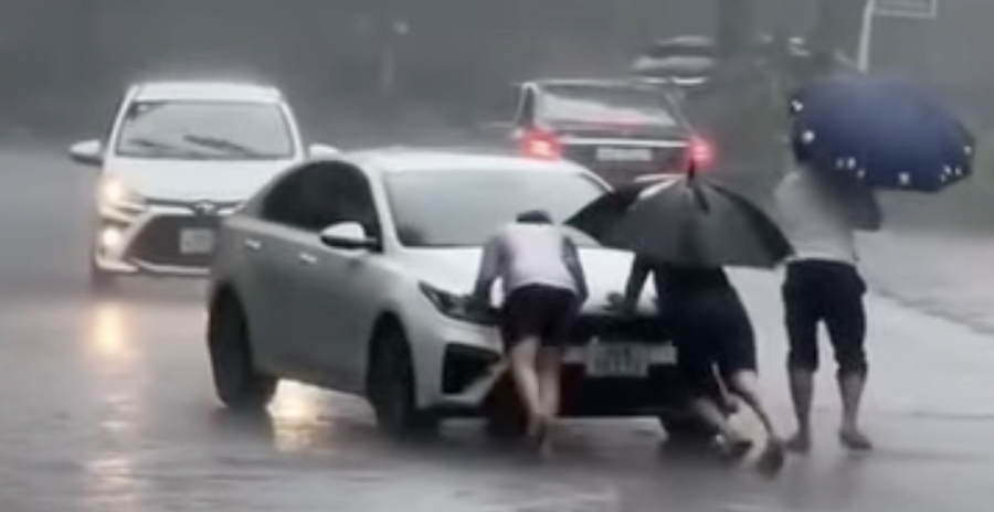 Một ô tô khác không thể di chuyển qua khu vực ngập sâu được người dân giúp đỡ thoát hiểm. (Ảnh: Cắt từ Clip).