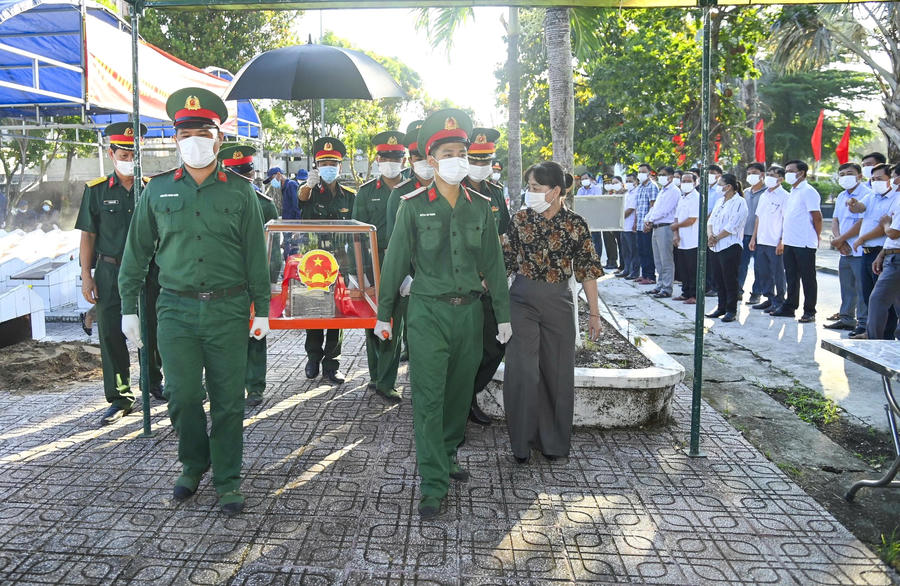 Cán bộ, chiến sĩ Bộ CHQS tỉnh Cà Mau cùng lực lượng địa phương thành kính di chuyển quách hài cốt liệt sĩ phục vụ quá trình lấy mẫu sinh phẩm. (Ảnh: VĐ).