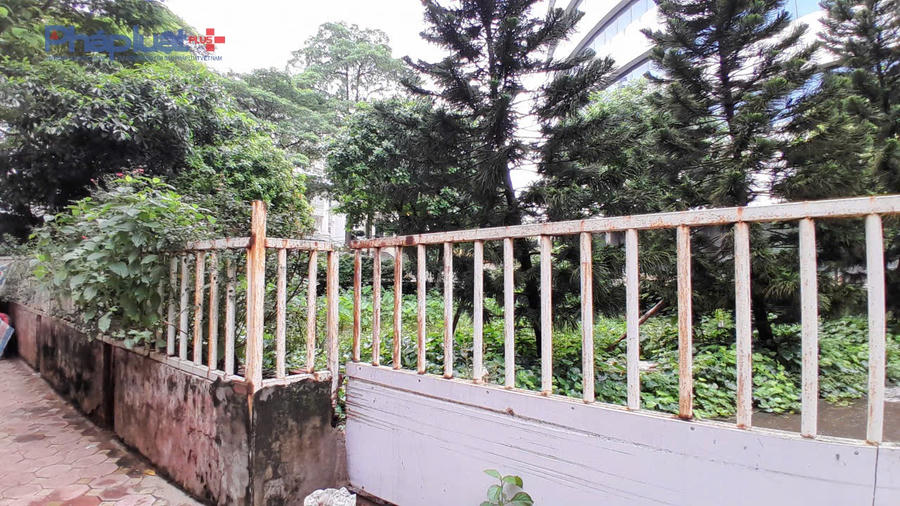 Khoá cổng đã rỉ sét, sau cánh cổng, hàng rào là cây cối mọc um tùm, kết cấu công trình có dấu hiệu xuống cấp do lâu không đưa vào sử dụng.