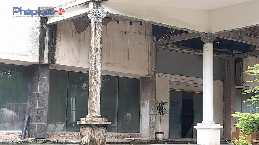 Khoá cổng đã rỉ sét, sau cánh cổng, hàng rào là cây cối mọc um tùm, kết cấu công trình có dấu hiệu xuống cấp do lâu không đưa vào sử dụng.