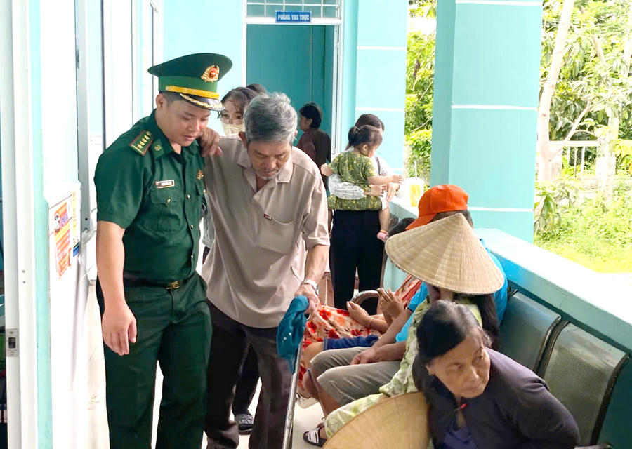 Cán bộ Đồn Biên phòng Đất Mũi hỗ trợ người dân đi lại khó khăn đến nơi khám mắt.