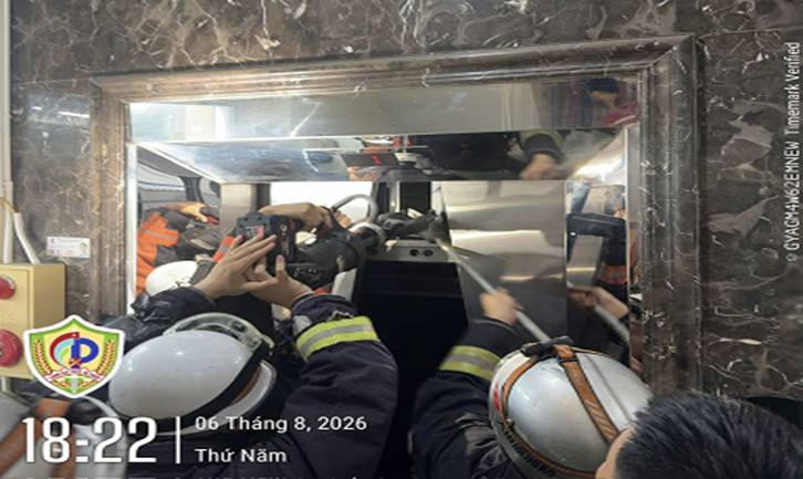 Lực lượng Cảnh sát PCCC&CNCH sử dụng kìm chuyên dụng để mở cửa thang máy bị kẹt. (Ảnh: Công an TP Hà Nội)