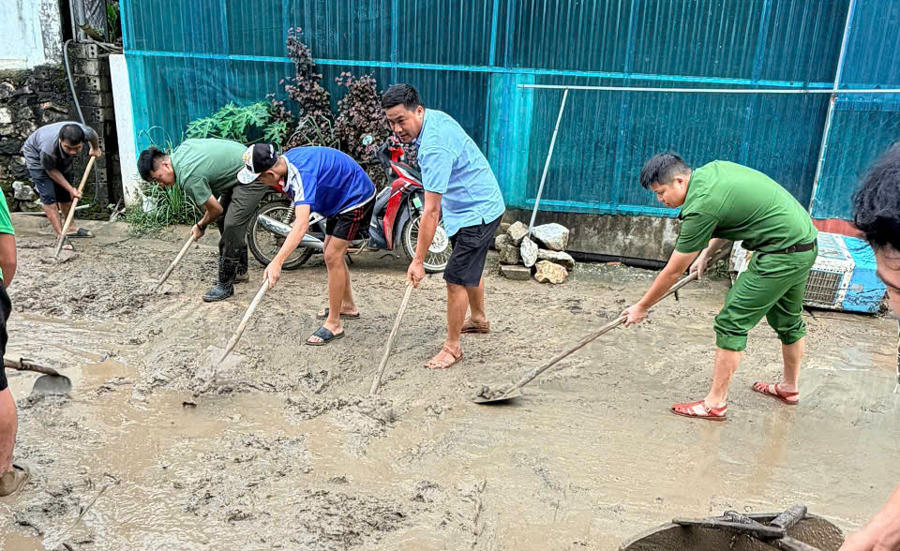Công an xã Mường Chanh cùng các lực lượng hỗ trợ người dân dọn dẹp bùn đất tràn xuống đường.