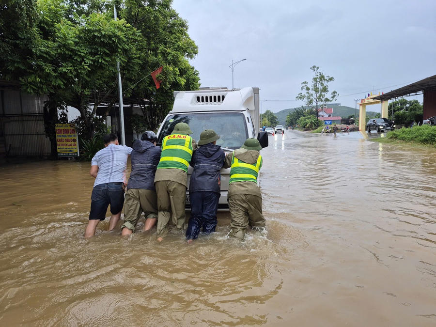 Công an xã Trường Sơn hỗ trợ người dân di chuyển xe bị chết máy ở đoạn nước ngập sâu.