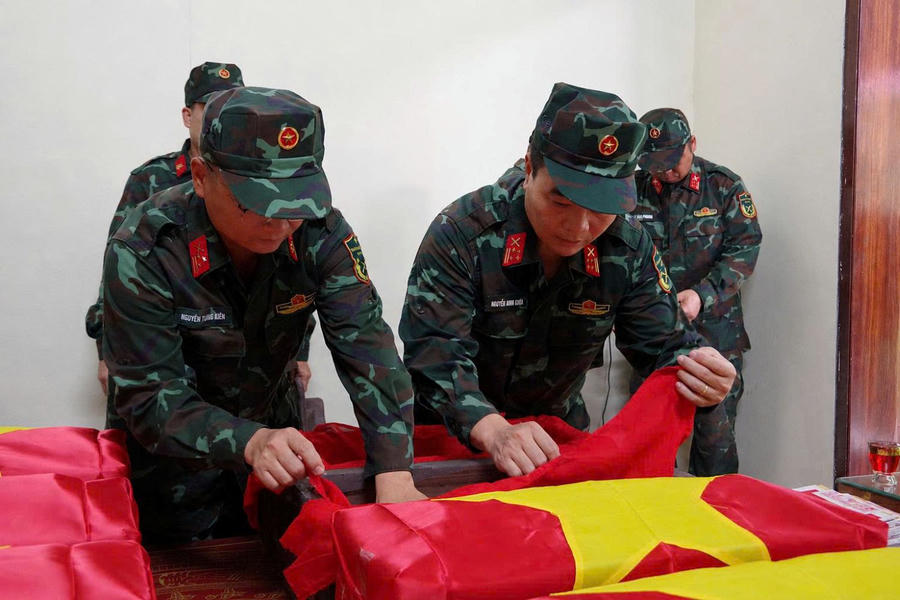 Đại tá Nguyễn Minh Khôi và Thượng tá Nguyễn Trung Kiên thực hiện nghi lễ đưa hài cốt liệt sĩ vào áo quan và phủ Cờ Tổ quốc.