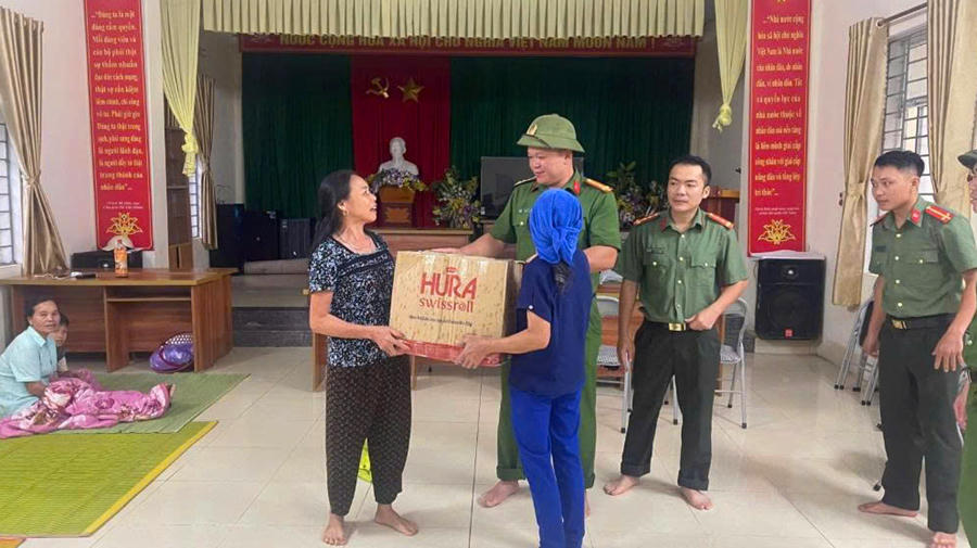 Công an xã Trung Hạ hỗ trợ nhu yếu phẩm cho người dân bị ảnh hưởng phải di dời đến nơi tránh trú. (Ảnh: CATH)