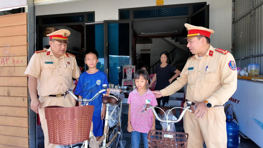 Cán bộ Phòng CSGT Công an thành phố Quảng Ninh trao xe đạp, động viên hai học sinh có hoàn cảnh đặc biệt trước thềm năm học mới.