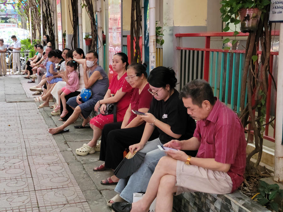 Trái ngược với sự náo nhiệt bên trong, một góc hành lang lại hiện lên thật đầm ấm và bình dị với hình ảnh các bậc phụ huynh kiên nhẫn ngồi đợi, lặng lẽ làm hậu phương vững chắc dõi theo từng bước đi của con trẻ.