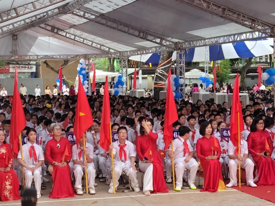 Sắc áo dài đỏ thắm của các cô giáo hòa quyện cùng màu cờ, tạo nên một bức tranh rực rỡ, tươi vui và ngập tràn tình cảm cô trò ấm áp.