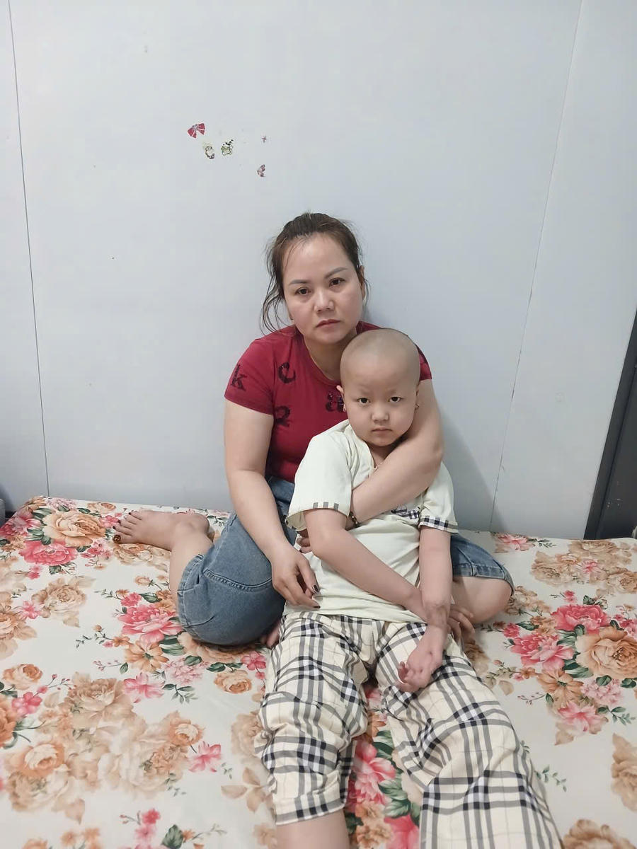 Chị Vũ Thị Xuân Hồng lặng lẽ ôm con trong vòng tay, trở thành điểm tựa yêu thương và tiếp thêm nghị lực để bé vững vàng vượt qua bệnh tật.