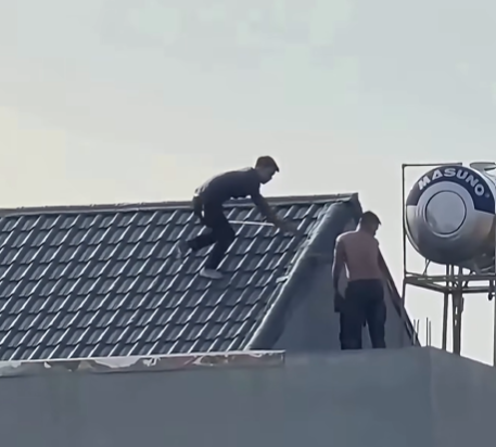 Hai đối tượng cùng hung khí trên nóc nhà (Ảnh chụp màn hình)