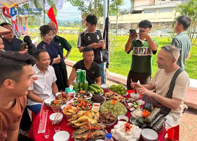 Du khách quốc tế thích thú trải nghiệm hương vị các món ăn truyền thống tại Hội thi mâm cơm mới xã Lục Hồn.Ảnh: Báo Quảng Ninh